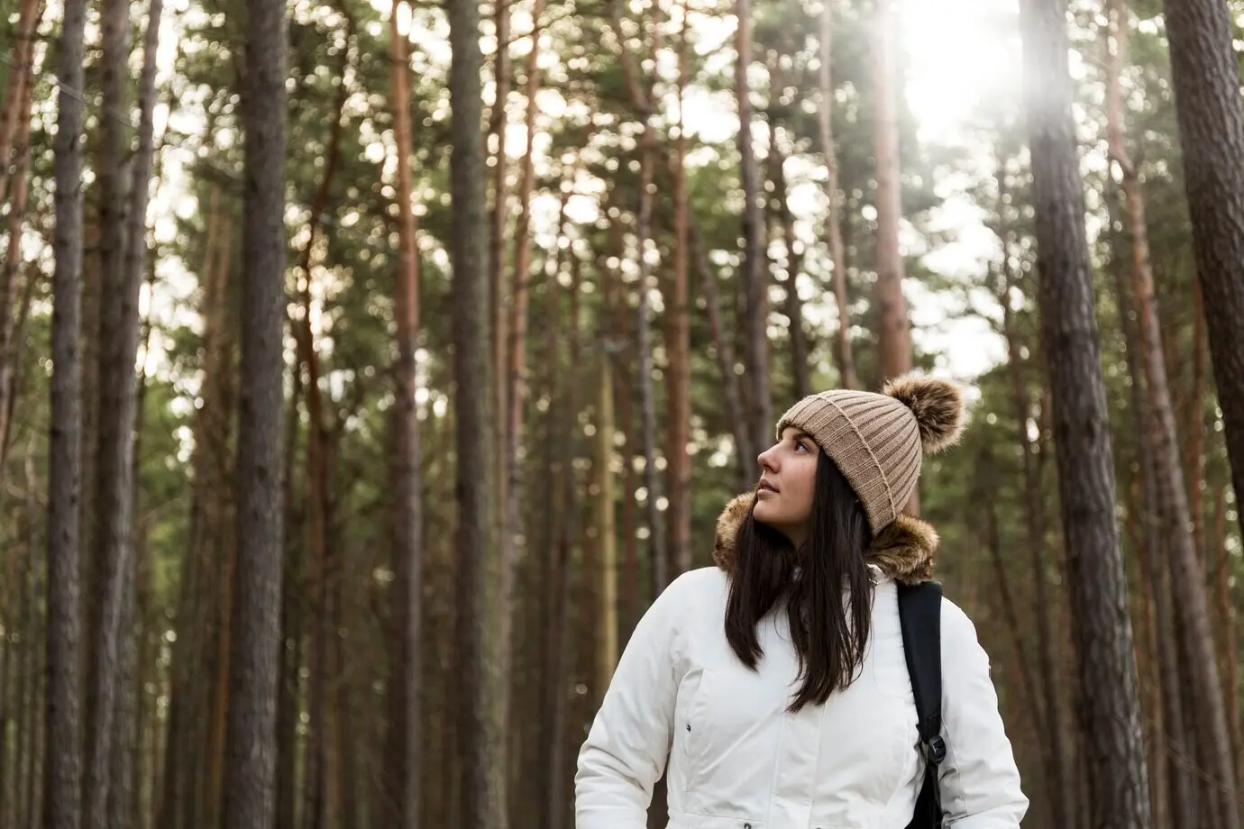 Eine Frau in einem Wald, die nach oben schaut.